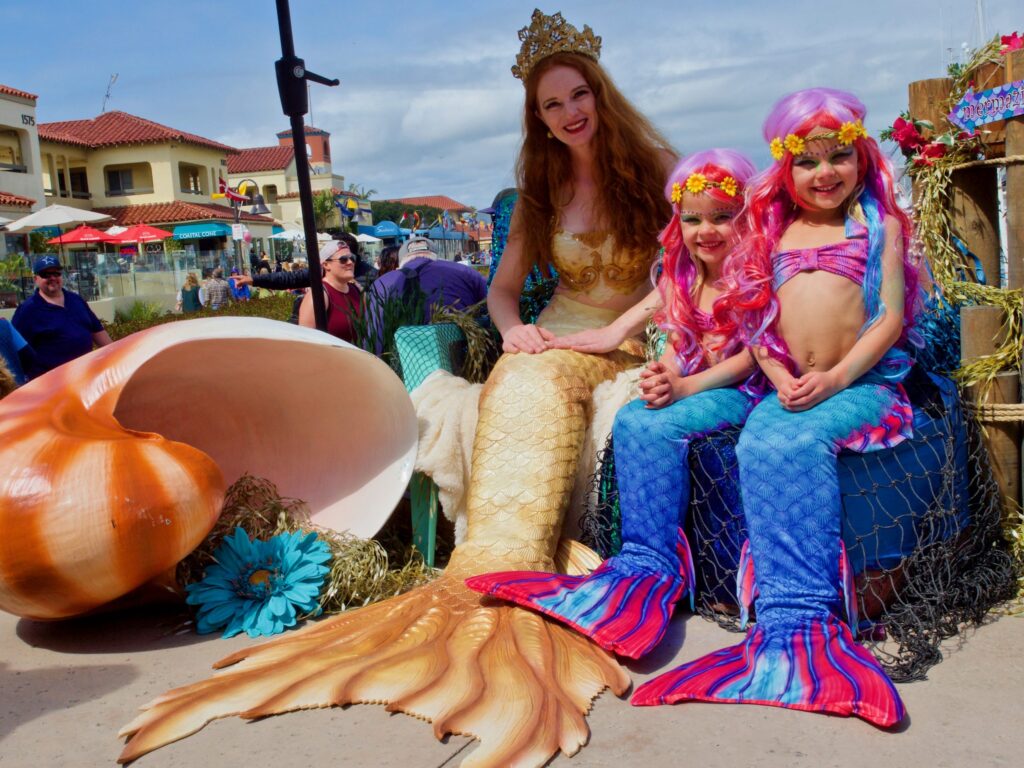 Adult mermaid sitting with two little merfolk for a photo op